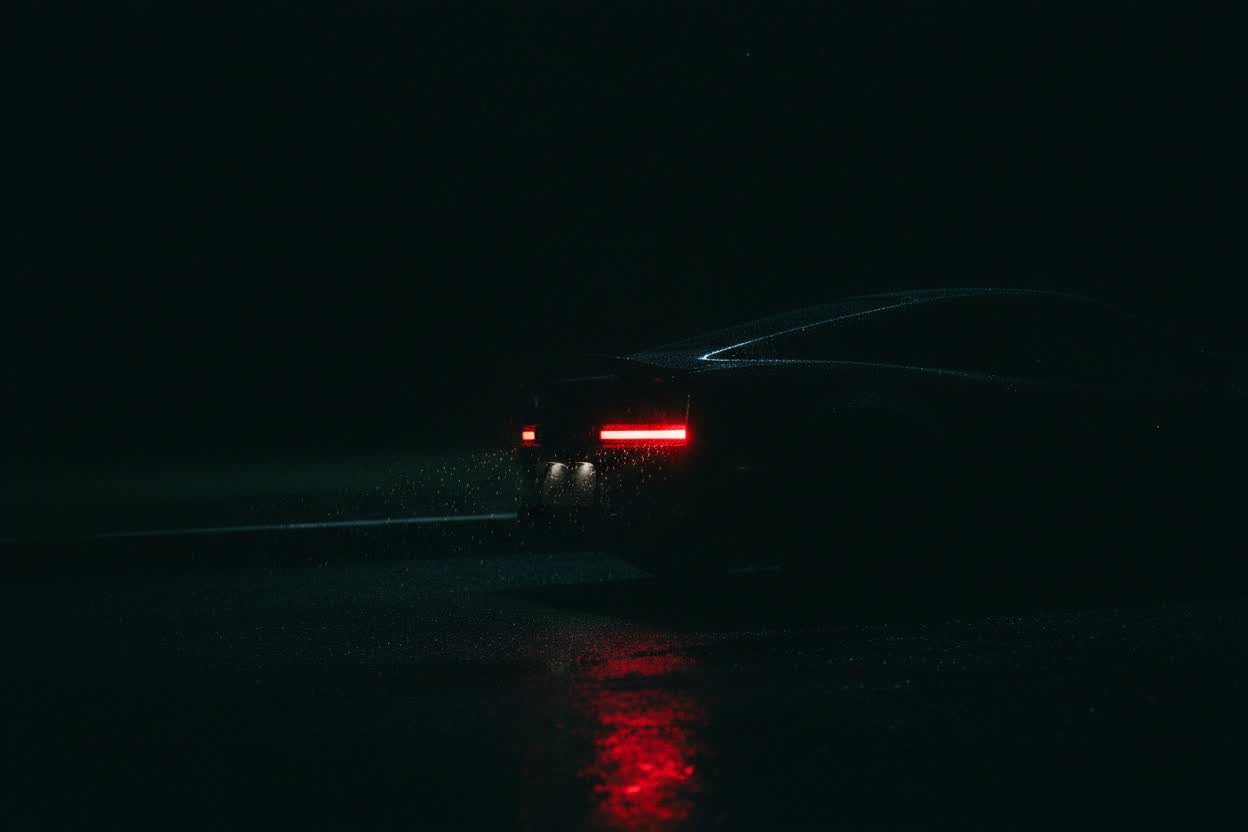 Taillights glowing through rain on a dark street